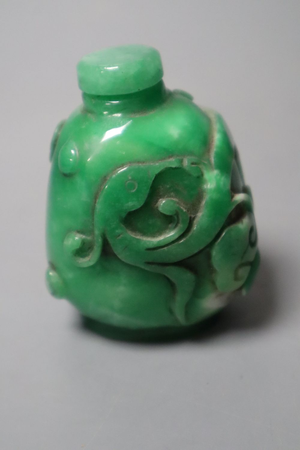 A Chinese green jadeite snuff bottle and stopper, a similar phoenix & dragon bangle and an archers ring